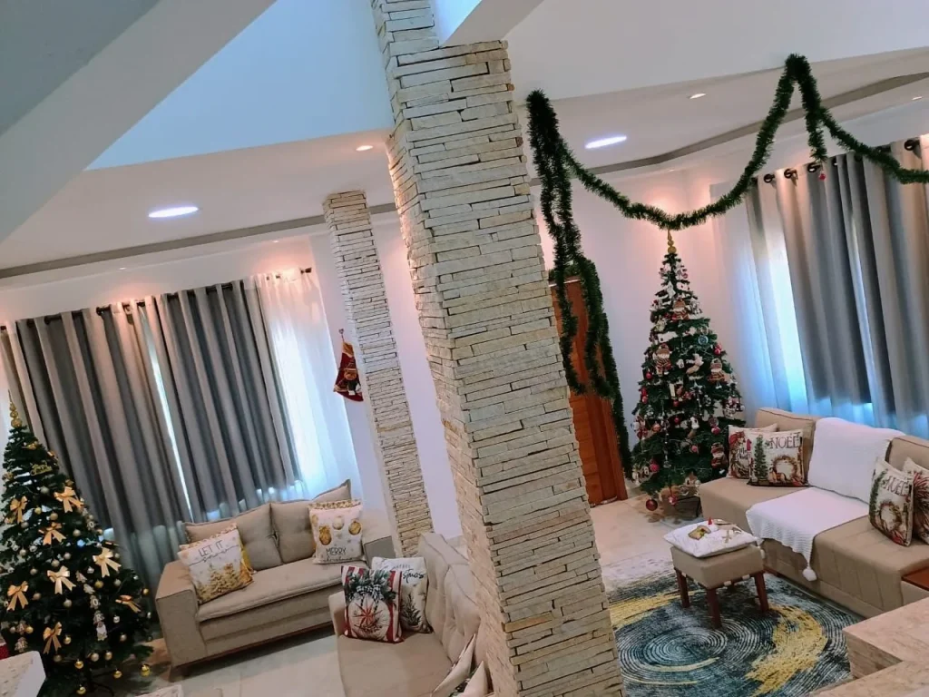 Sala de convivência com pilares de pedra e guirlanda